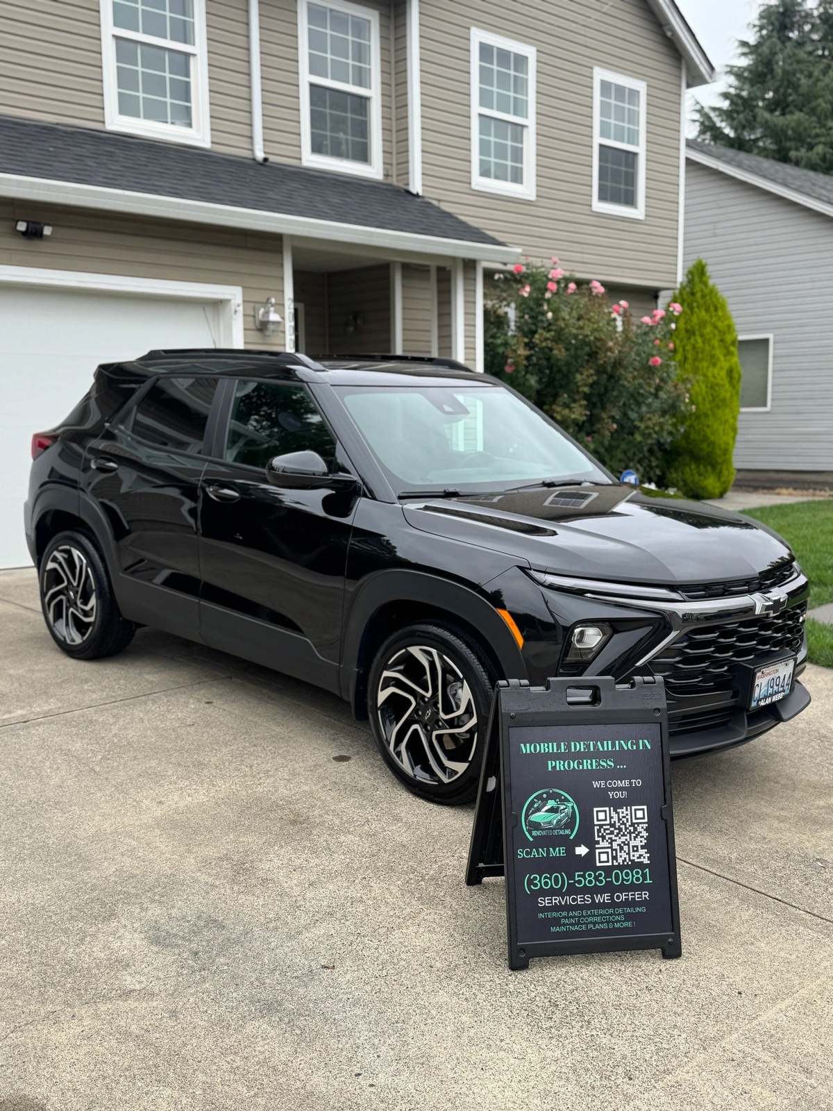 Black Chevy Trailblazer finished, mobile detailing sign set beside it